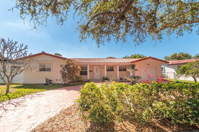 view of front of property with a front yard, a tiled roof, an attached garage, and stucco siding