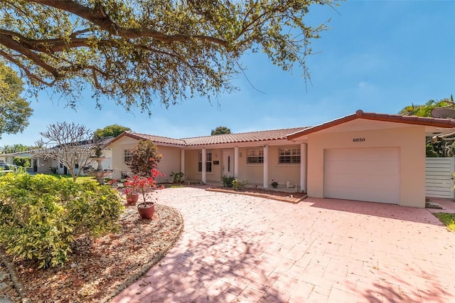 single story home featuring a tile roof, decorative driveway, an attached garage, and stucco siding