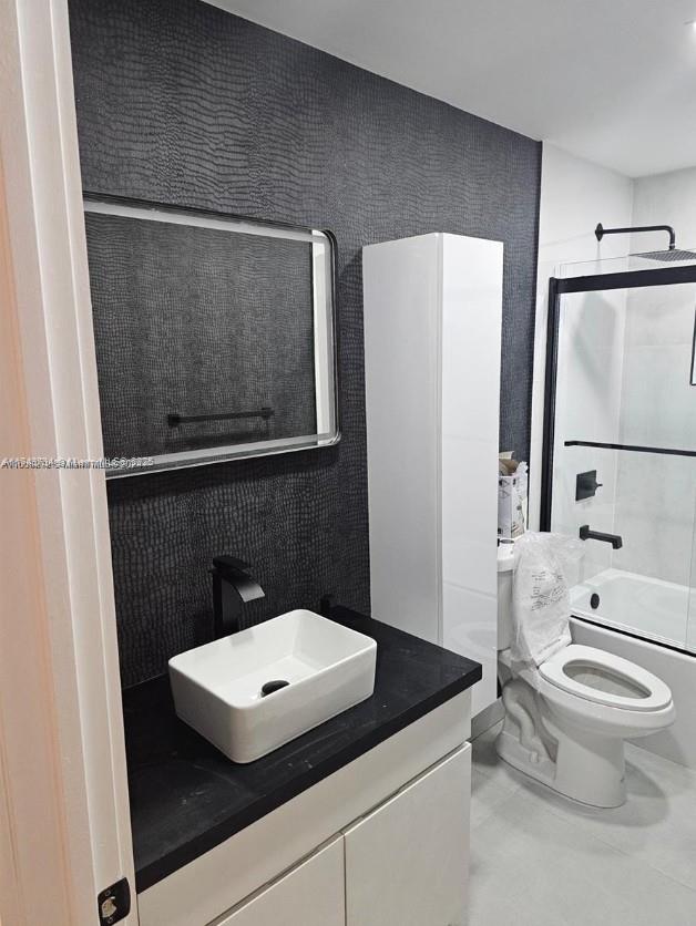 bathroom featuring vanity, toilet, and enclosed tub / shower combo