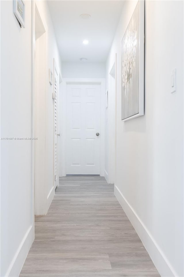 hallway with light wood-type flooring and baseboards