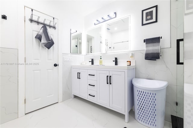 full bathroom with double vanity, marble finish floor, tile walls, and a sink