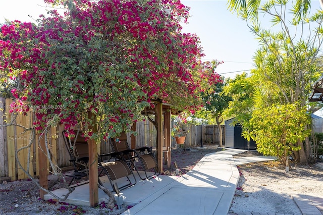 view of patio / terrace featuring an outbuilding, a storage unit, and a fenced backyard