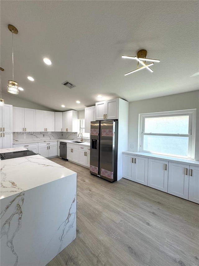 kitchen with visible vents, stainless steel refrigerator with ice dispenser, light stone counters, a sink, and dishwasher