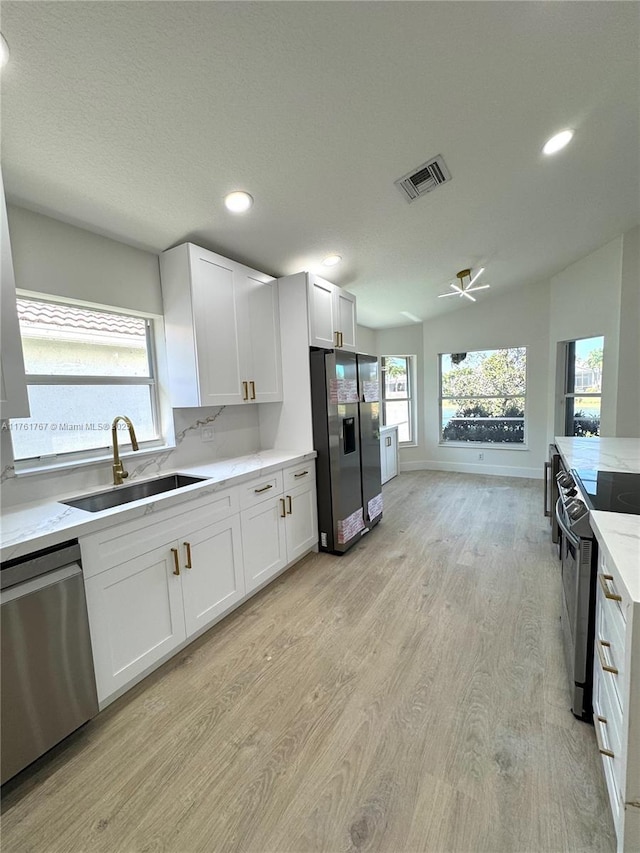 kitchen with light wood finished floors, a sink, black range with electric stovetop, stainless steel dishwasher, and refrigerator with ice dispenser