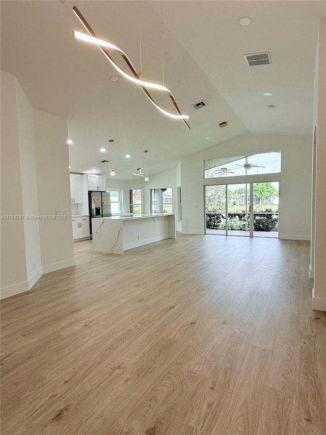 9785 San Luca St, Lake Worth, FL 33467 - unfurnished living room featuring baseboards, plenty of natural light, light wood-type flooring, lofted ceiling, and recessed lighting