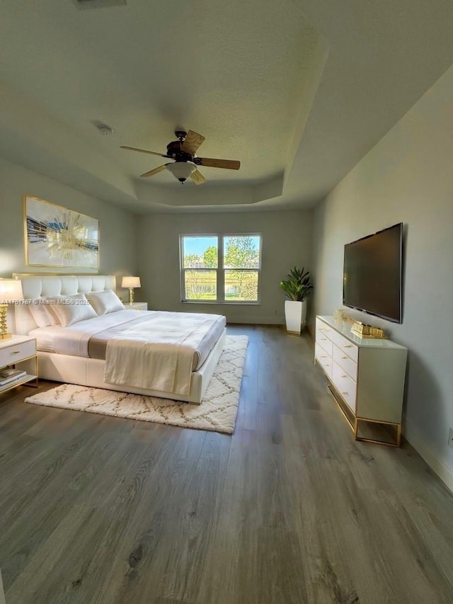 9785 San Luca St, Lake Worth, FL 33467 - bedroom featuring a tray ceiling, wood finished floors, baseboards, and a ceiling fan