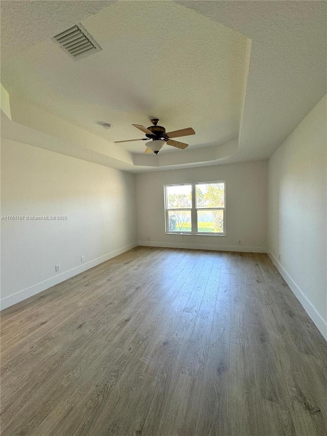 9785 San Luca St, Lake Worth, FL 33467 - spare room with a ceiling fan, wood finished floors, a textured ceiling, baseboards, and a raised ceiling