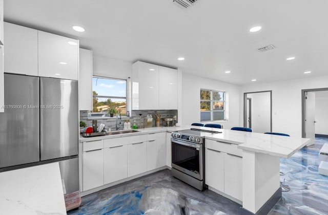 kitchen featuring visible vents, modern cabinets, white cabinetry, stainless steel appliances, and a peninsula