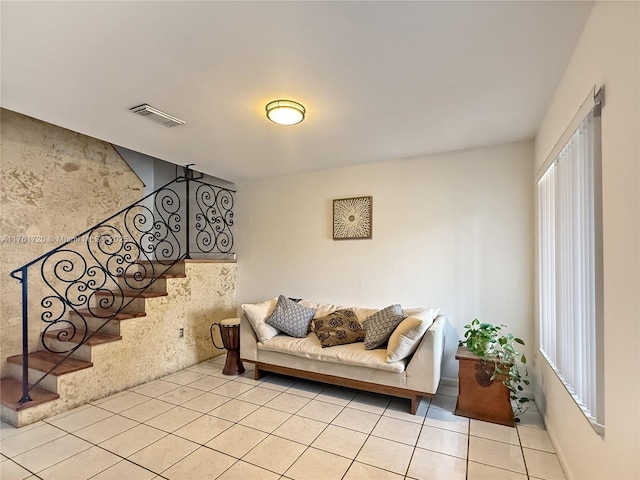 living room with light tile patterned floors, visible vents, and stairway