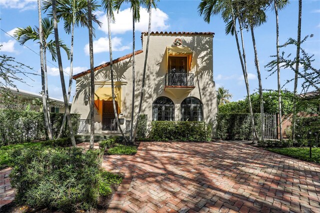 view of front of property with a balcony, fence, and stucco siding