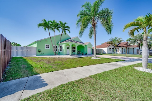 exterior space featuring concrete driveway, a front yard, an attached garage, and fence private yard