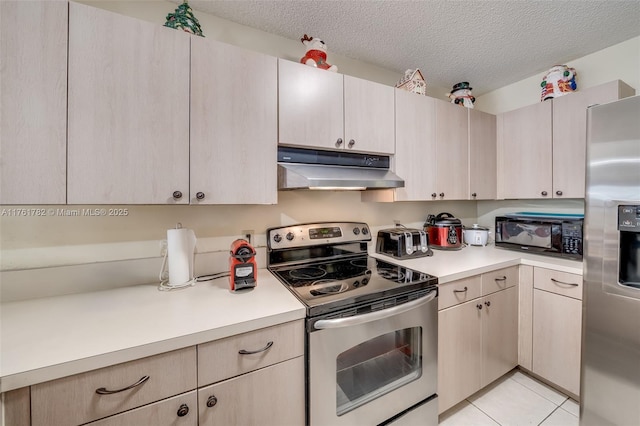 kitchen featuring light tile patterned flooring, light countertops, appliances with stainless steel finishes, a textured ceiling, and under cabinet range hood