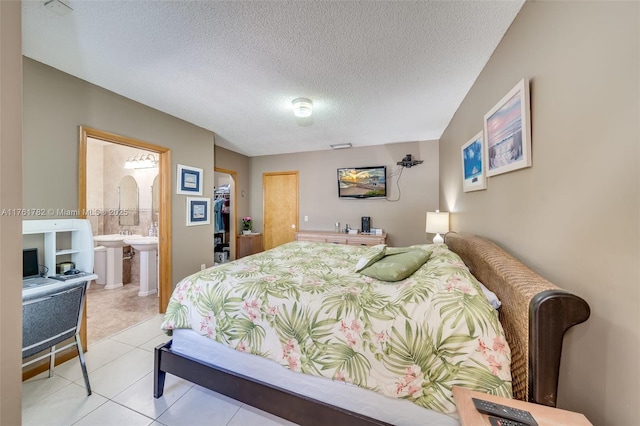 bedroom featuring ensuite bath, a textured ceiling, and light tile patterned floors