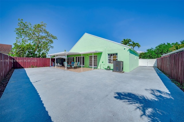 rear view of house featuring cooling unit, stucco siding, a fenced backyard, a gate, and a patio area