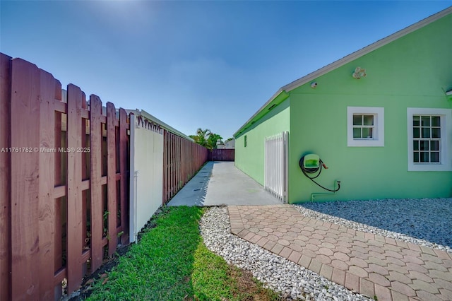 view of side of home featuring a fenced backyard, stucco siding, and a patio area