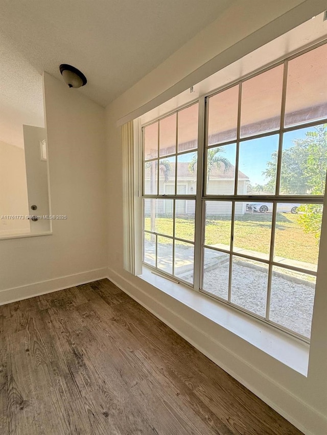 empty room featuring dark wood-type flooring and baseboards