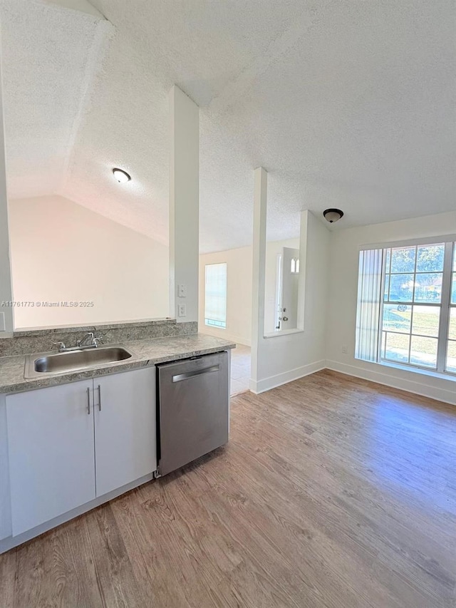 kitchen featuring white cabinetry, a sink, vaulted ceiling, light wood-style floors, and dishwasher