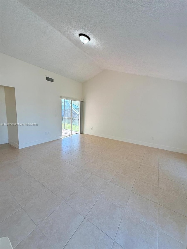 unfurnished room featuring visible vents, a textured ceiling, baseboards, and lofted ceiling