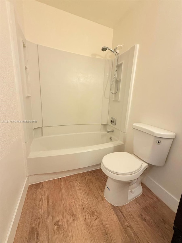 bathroom featuring toilet, wood finished floors, baseboards, and shower / bath combination