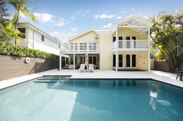 back of property with an outdoor pool, french doors, fence, and a patio area