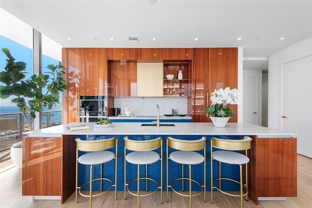 kitchen featuring modern cabinets, visible vents, backsplash, and a sink