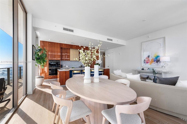 dining room with visible vents, light wood-style flooring, and expansive windows