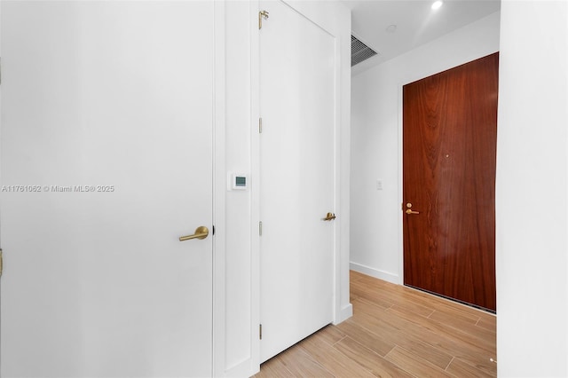 hallway featuring visible vents, baseboards, and light wood-style floors