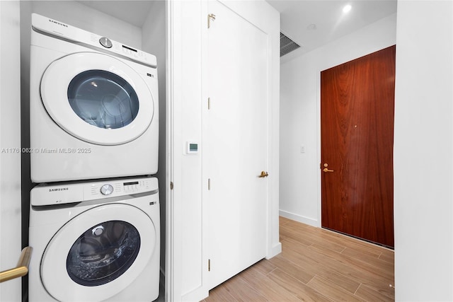 laundry area with visible vents, baseboards, laundry area, light wood-style flooring, and stacked washer / drying machine