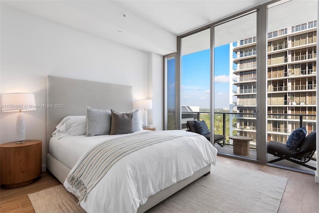 bedroom featuring access to outside, wood finished floors, and expansive windows