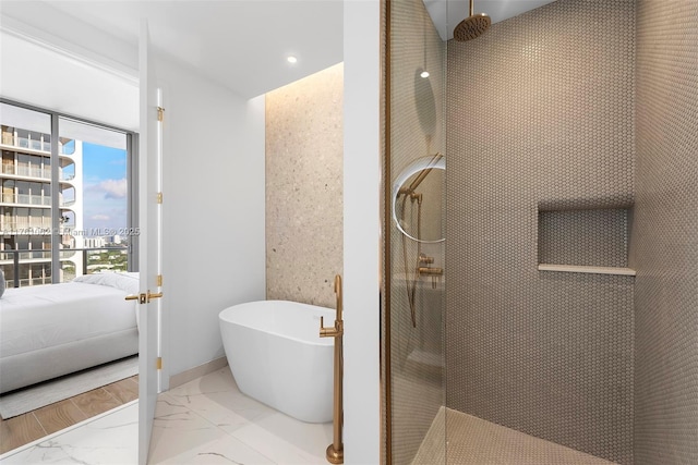 full bath featuring a freestanding tub, a walk in shower, marble finish floor, and ensuite bathroom