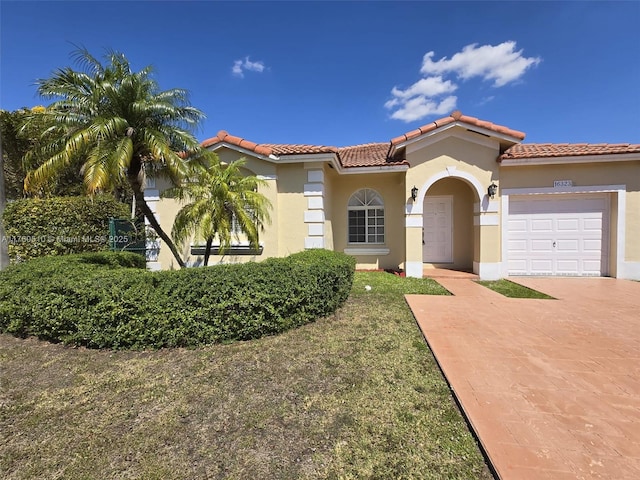 mediterranean / spanish house featuring stucco siding, a garage, driveway, and a tiled roof