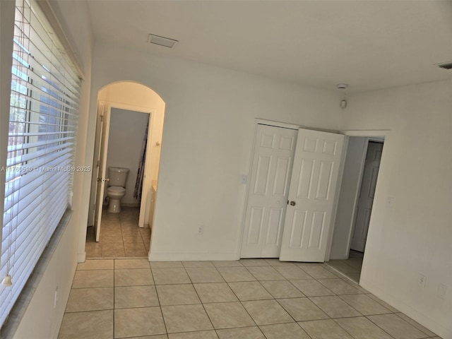 empty room with light tile patterned floors and arched walkways