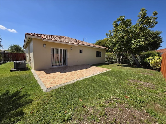 back of property with a lawn, a tile roof, a fenced backyard, and stucco siding