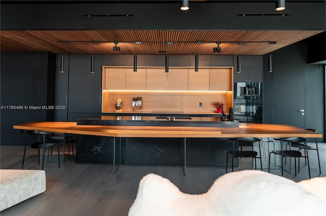 bar featuring wood finished floors, tasteful backsplash, and dobule oven black