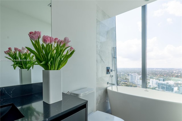 bathroom with vanity, a freestanding tub, and toilet