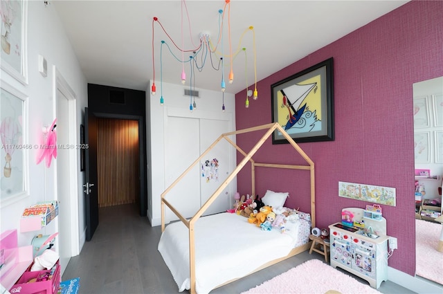 bedroom with visible vents, wood finished floors, and an accent wall