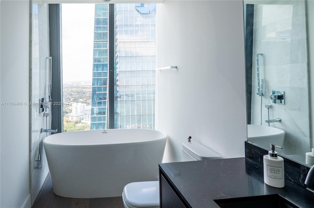 bathroom featuring a soaking tub, vanity, and toilet