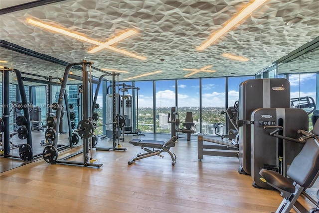 workout area with a wall of windows and wood-type flooring