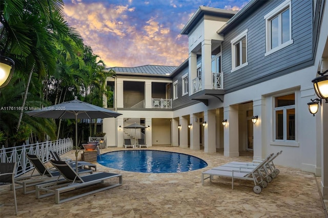 pool at dusk featuring a fenced in pool and a patio