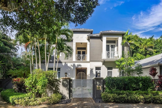 view of front of home with stucco siding, a balcony, and a gate