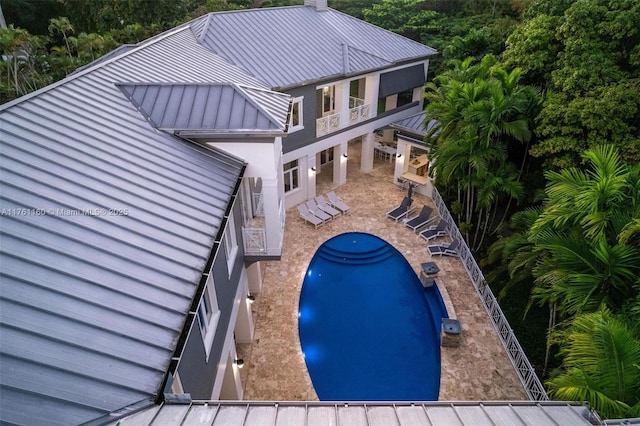 back of house with stucco siding, metal roof, a balcony, a patio area, and a standing seam roof