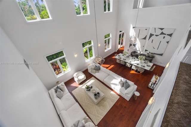 living room with a high ceiling, baseboards, and wood finished floors