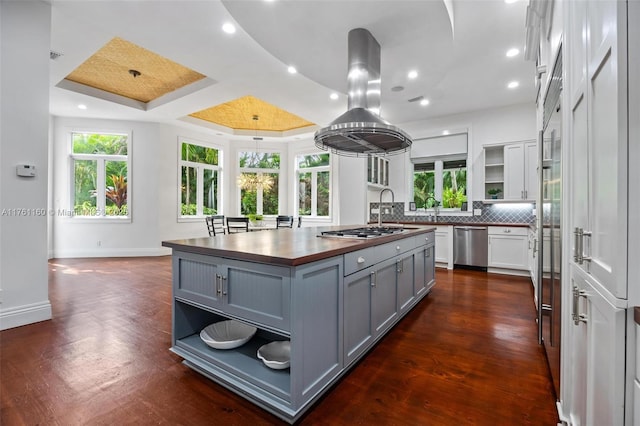 kitchen featuring gray cabinetry, a center island with sink, butcher block counters, appliances with stainless steel finishes, and open shelves