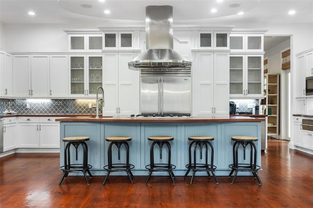 kitchen with built in appliances, white cabinetry, island exhaust hood, and dark wood-type flooring