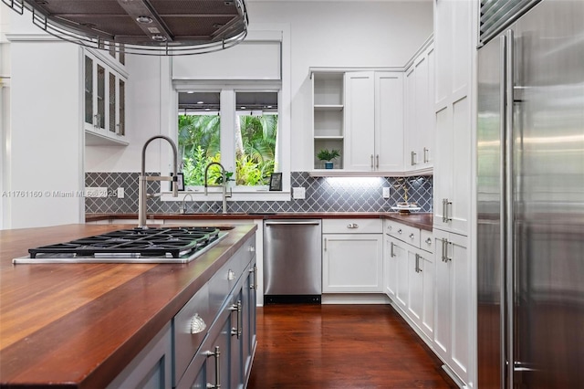 kitchen with ventilation hood, stainless steel appliances, decorative backsplash, dark wood-type flooring, and white cabinets