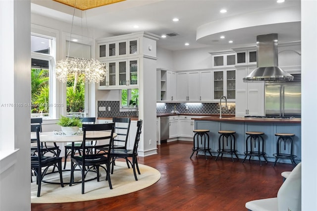 kitchen featuring visible vents, dark wood finished floors, appliances with stainless steel finishes, white cabinetry, and island range hood