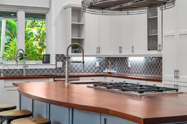 kitchen with tasteful backsplash, butcher block counters, white cabinetry, and a sink