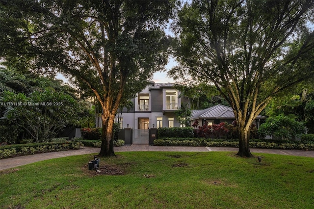 view of front of house with a front lawn, metal roof, driveway, and a standing seam roof