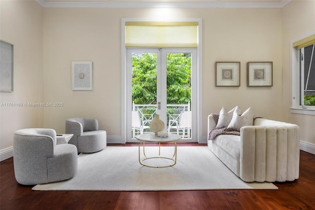 living area with baseboards, wood finished floors, and ornamental molding