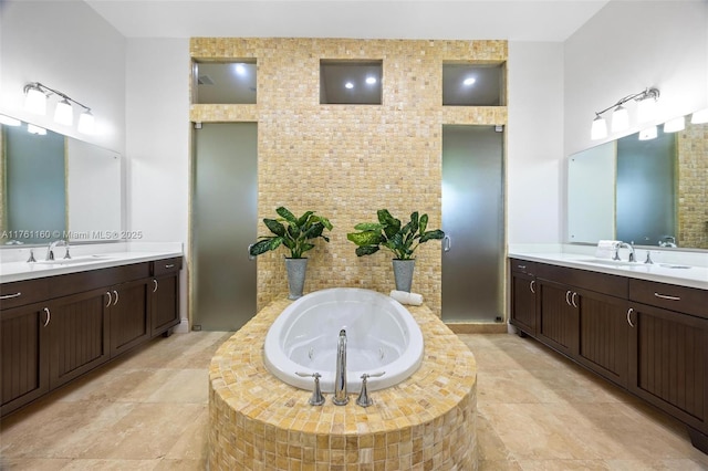 full bathroom with a jetted tub, two vanities, and a sink